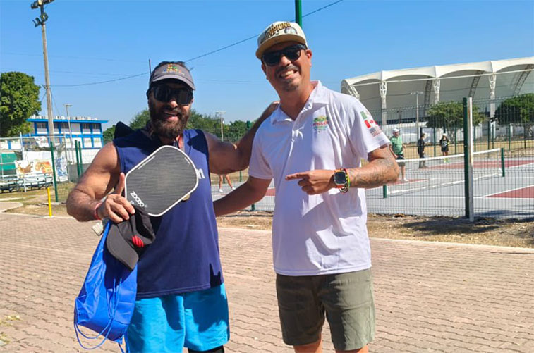 Mono and a fellow player posing at the Pata Salada Mazatlán Pickleball Club courts with the IMDEM stadium in the background.