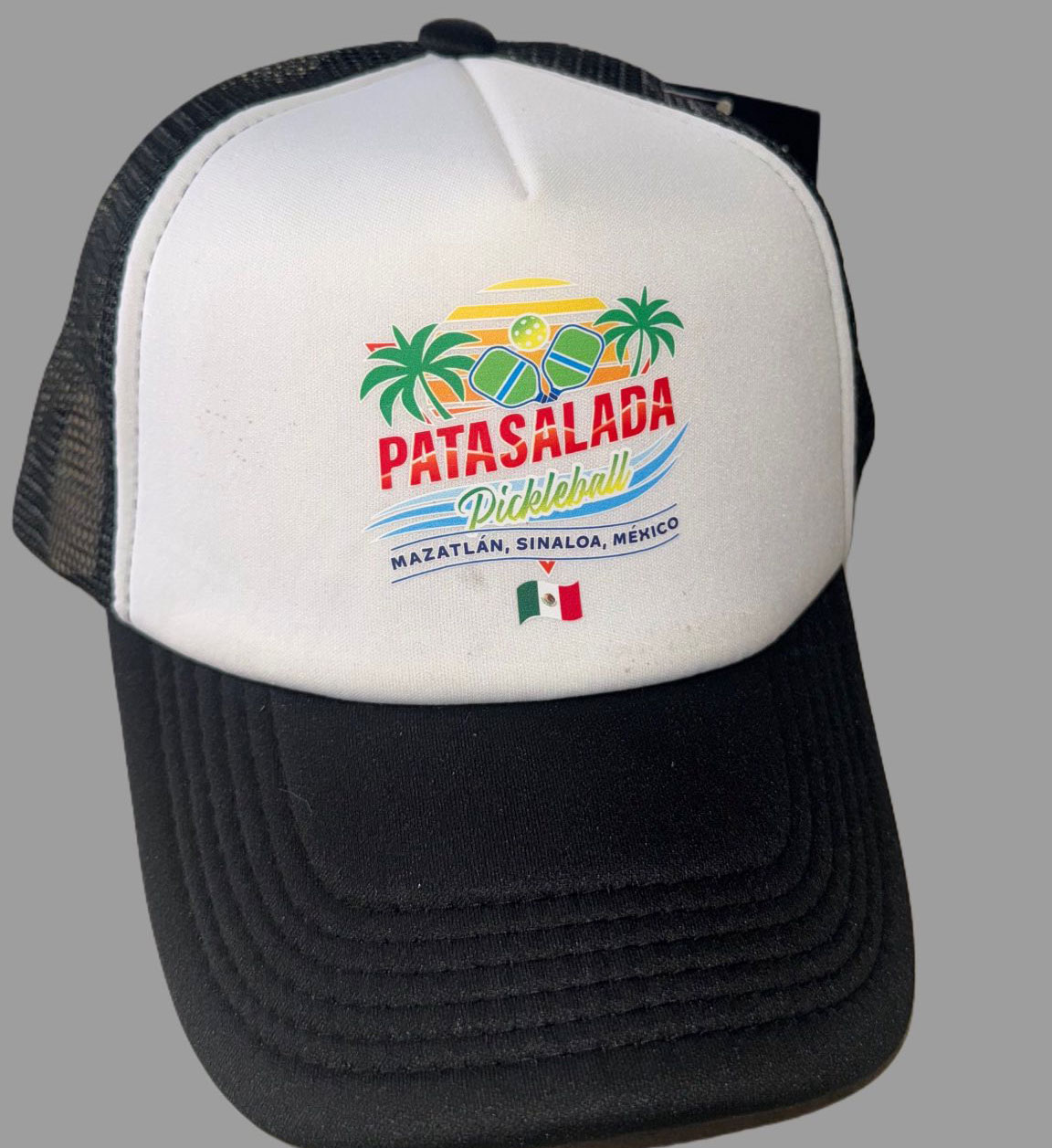 A black and white trucker-style hat with a mesh back, featuring the colorful Pata Salada Pickleball logo and a small Mexican flag on the front foam panel.