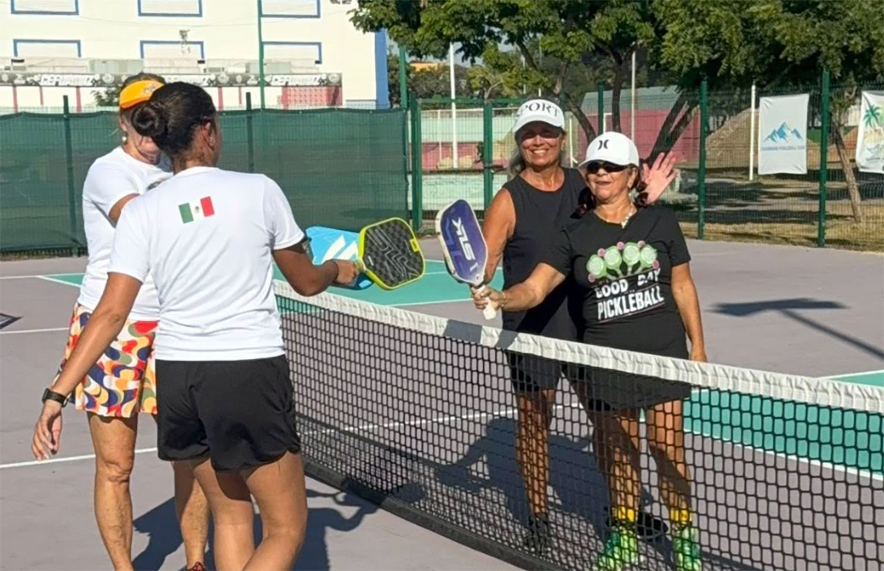 Four pickleball players tapping paddles after a game
